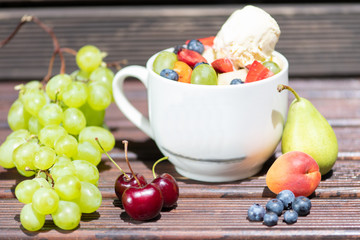 Bowl of healthy fresh fruit salad with ice cream on the wooden background.