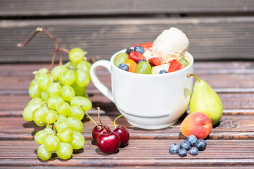 Bowl of healthy fresh fruit salad with ice cream on the wooden background.