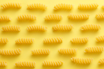 Raw fusilli pasta over yellow background.jpg