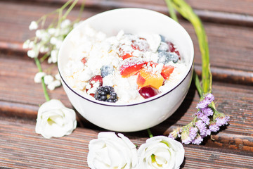 Bowl of healthy fresh fruit salad with cheese on the wooden background.