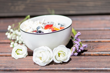 Bowl of healthy fresh fruit salad with cheese on the wooden background.