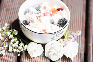 Bowl of healthy fresh fruit salad with cheese on the wooden background.