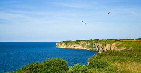 Fototapeta na wymiar Pointe du Hoc cliffs in clear sky and calm sea. One of the places where took place Normandy Landing. France.