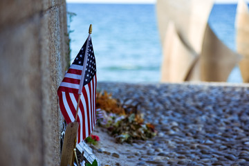 United States flag, flowers and objects in memory of fallen in Normandy landing. Omaha Beach...