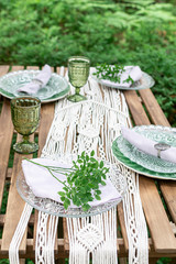 Boho style wedding reception dinning table with macrame tablecloth, decoration on a rustic wooden table