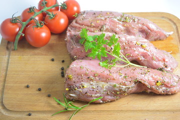 raw pork filet for grill with olive oil salt pepper and vegetables on a wooden plate