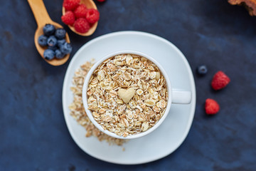 Raspberries and blueberries on blue background. Cereals.