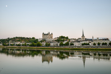 Fototapeta na wymiar Views of the city of Saumur from the riverbank at dusk, with the castle in the background. Loire Valley, France.