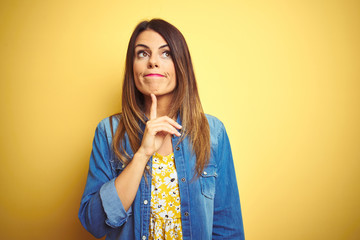 Young beautiful woman standing over yellow isolated background Thinking concentrated about doubt...