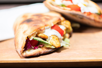 Healthy grilled chicken sandwich with homemade baguette on a wooden plate.