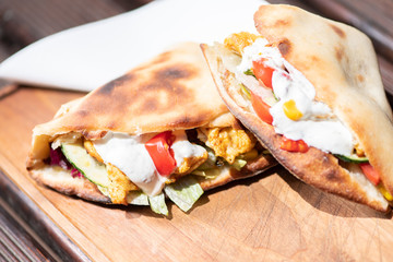 Healthy grilled chicken sandwich with homemade baguette on a wooden plate.