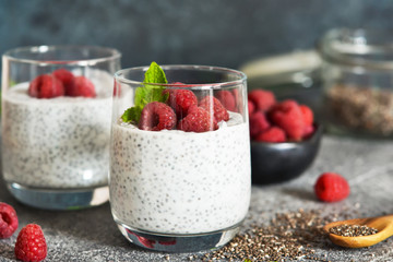 Chia pudding with yogurt and raspberries in a glass on concrete background