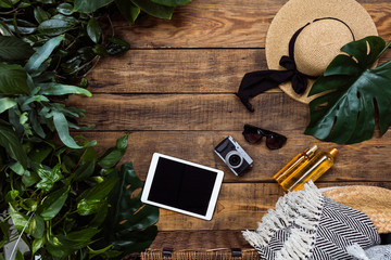 Top view of group of summer objects on wooden background. Sunhat, sunglasses and exotic levies....