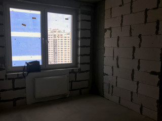 A window with a plastic profile in the new building with a free layout, in an apartment without repair, construction with a battery and walls of gas silicate blocks