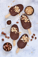 Chocolate popsicle with granola and nuts. Ice cream on a concrete background. Top view.