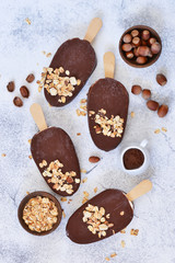 Chocolate popsicle with granola and nuts. Ice cream on a concrete background. Top view.