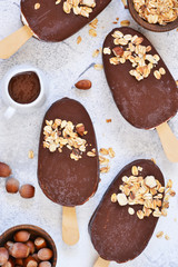 Chocolate popsicle with granola and nuts. Ice cream on a concrete background. Top view.