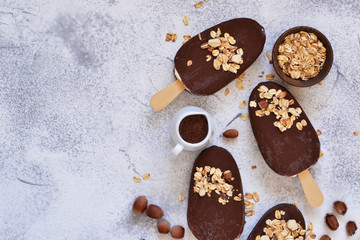 Chocolate popsicle with granola and nuts. Ice cream on a concrete background. Top view.