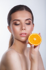 Beautiful woman with natural make up and orange on white background.