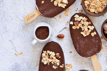 Chocolate popsicle with granola and nuts. Ice cream on a concrete background. Top view.