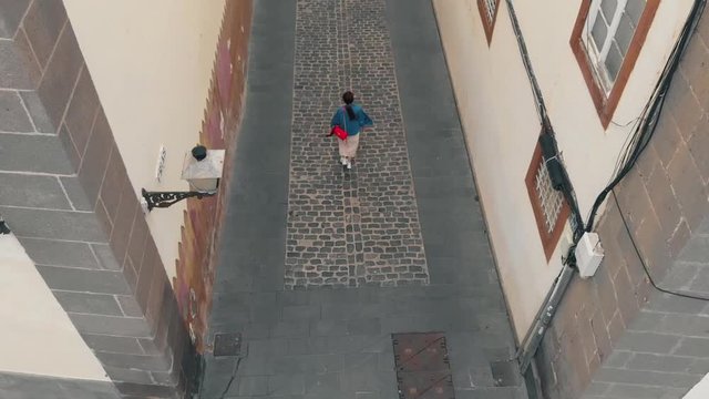 Top down view. A young woman walks along a narrow street of the old town in the capital of the island of Gran Canaria, a bird's-eye view.