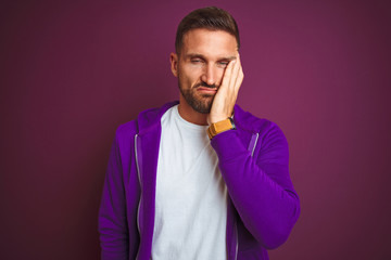 Fototapeta premium Young fitness man wearing casual sports sweatshirt over purple isolated background thinking looking tired and bored with depression problems with crossed arms.