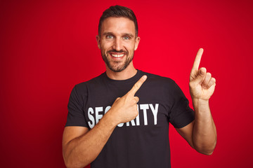 Young safeguard man wearing security uniform over red isolated background smiling and looking at...