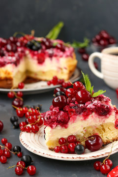 Summer cottage cheese cake with berries is located on a dark background, in the foreground a piece of cake on a plate, vertical photo