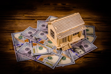 Plywood model of the house and one hundred dollar banknotes. Loan, real estate concept
