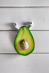 Avocado Isolated on White wood background wis headphones. Music Symbol or Fresh Organic Fruit for Healthy Lifestyle Concept - obrazy, fototapety, plakaty