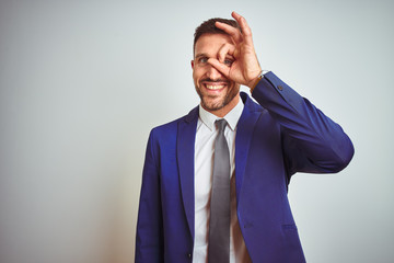 Young handsome business man over white isolated background doing ok gesture with hand smiling, eye looking through fingers with happy face.