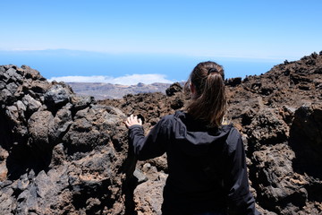 Woman ascending the Teide mountain peak on a dry and rocky volcanic landscape