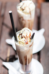 Ice coffee on a wood table with cream being poured into it showing the texture and refreshing look of the drink.