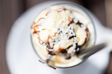 Ice coffee on a wood table with cream being poured into it showing the texture and refreshing look of the drink. Top view.