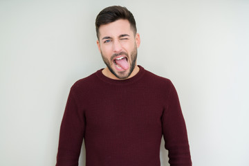 Fototapeta premium Young handsome man wearing a sweater over isolated background sticking tongue out happy with funny expression. Emotion concept.