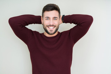 Young handsome man wearing a sweater over isolated background Relaxing and stretching with arms and hands behind head and neck, smiling happy