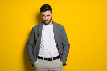 Young handsome man possing and modeling over yellow isolated background