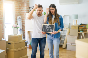 Fototapeta na wymiar Young beautiful couple holding blackboard with new home text at new house annoyed and frustrated shouting with anger, crazy and yelling with raised hand, anger concept