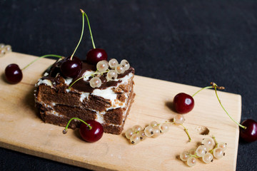 Top view of a slide of chocolate cake with a cherry on a black background