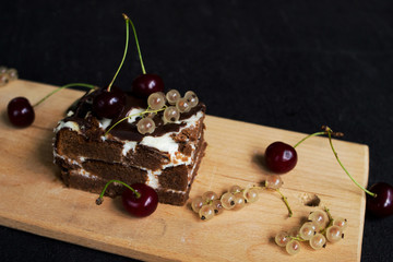 A slide of chocolate cake with a cherry on a black background