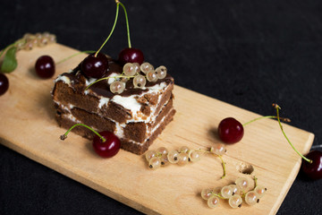 A slide of chocolate cake with a cherry on a black background