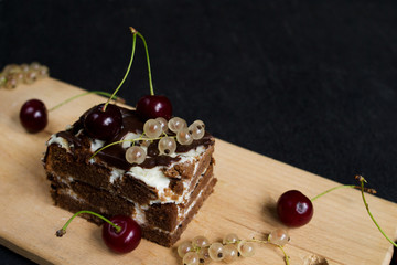 A slide of chocolate cake with a cherry on a black background