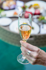 Close up image of a woman holding a glass of champagne, a meal next to the pool, leisure vacation travel summertime concept