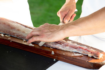 Chef hand cutting fresh piece of salmon