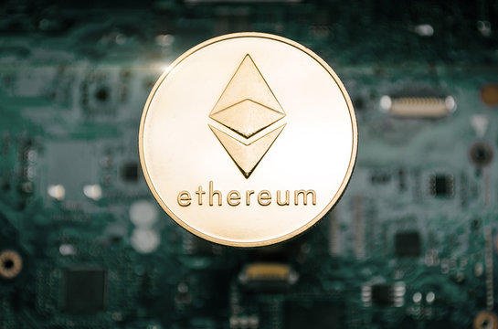 Gold etherum coin, on background of computer motherboard.