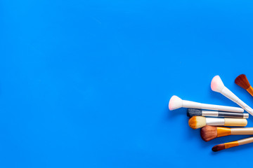 Brushes for make up on blue visagiste work desk background top view copyspace