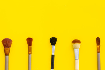 Instruments for make up with brushes on yellow background top view mock up