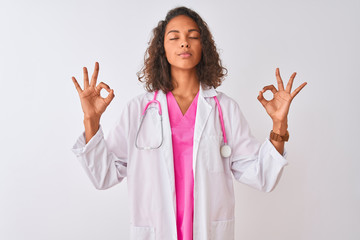 Young brazilian doctor woman wearing stethoscope standing over isolated white background relax and smiling with eyes closed doing meditation gesture with fingers. Yoga concept.