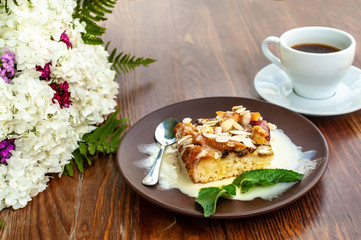 Still life with cake, cup of coffee and white small flower bouquet on aged wooden table or plate