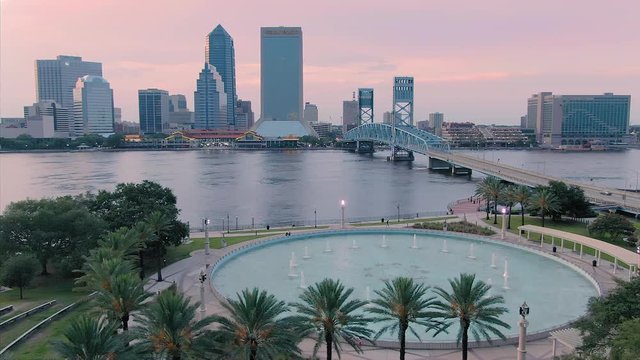 Aerial: Establishing shot of Jacksonville, st Johns river, large fountain & John T Alsop Jr bridge at sunset. Florida, USA. 2 July 2019